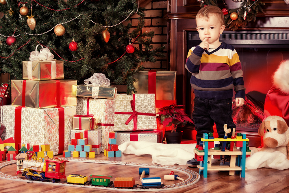 enfant regardant un mont de cadeaux de noël au pied du sapin