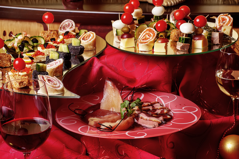 Table de réveillon comportant trois plateaux d'amuse-bouches et un verre de vin rouge