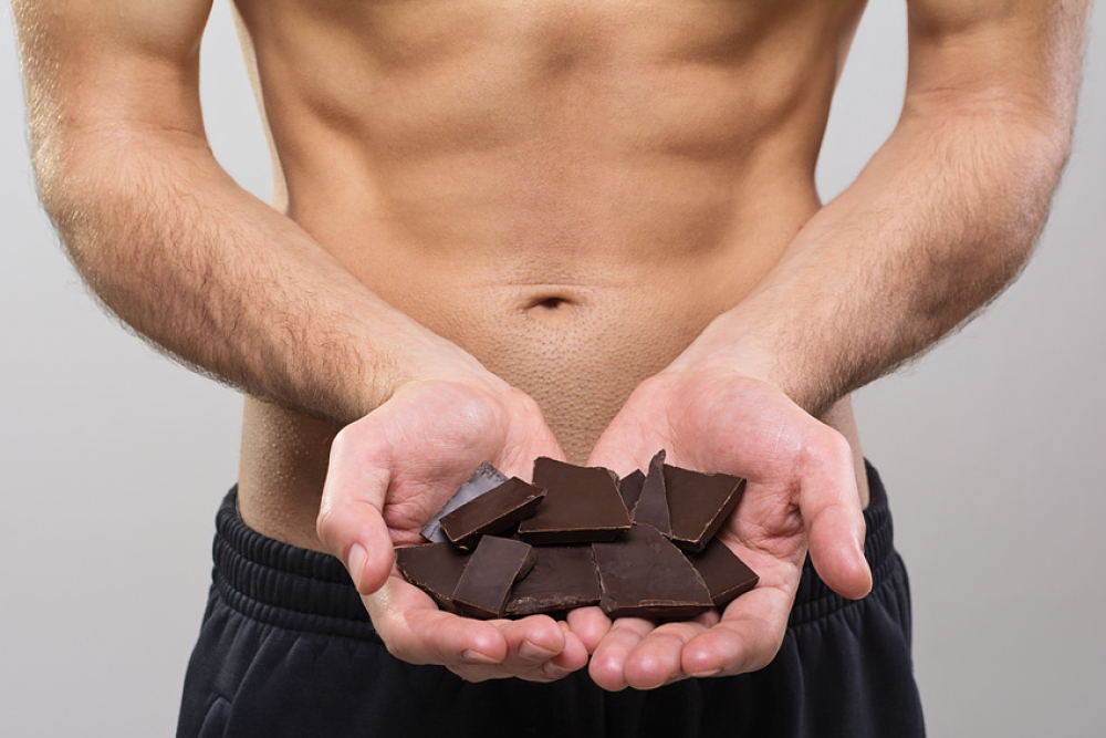 Homme musclé tenant du chocolat noir dans le creux de ses mains