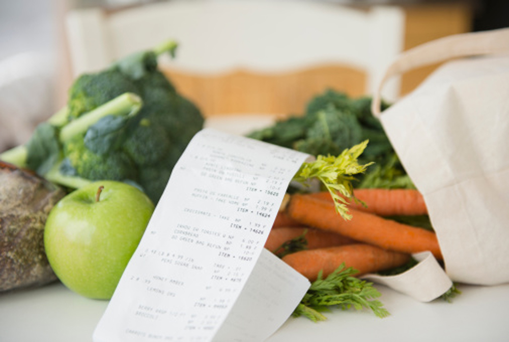 légumes et ticket de caisse sur une table blanche