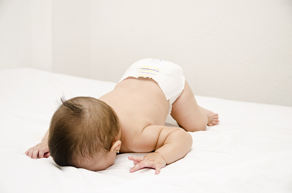 Bébé sur le ventre le visage contre le lit