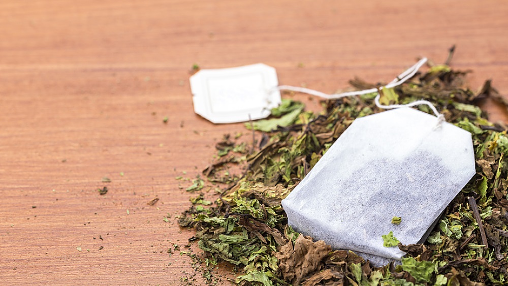 sachet de thé posé sur un petit amas de feuilles de thé séchées