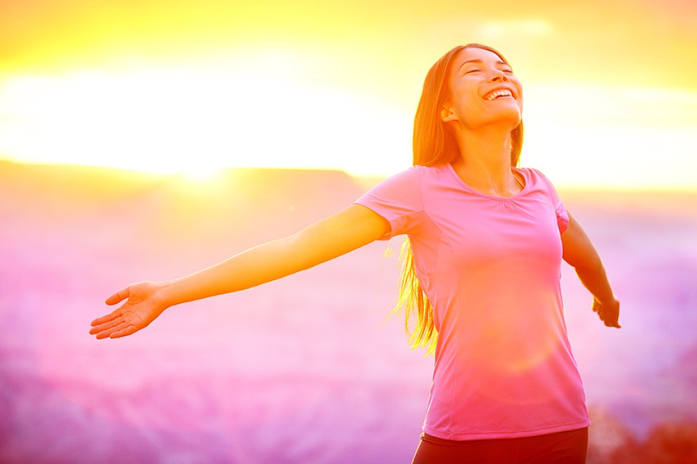 femme ouvrant les bras sur un fond de paysage rose