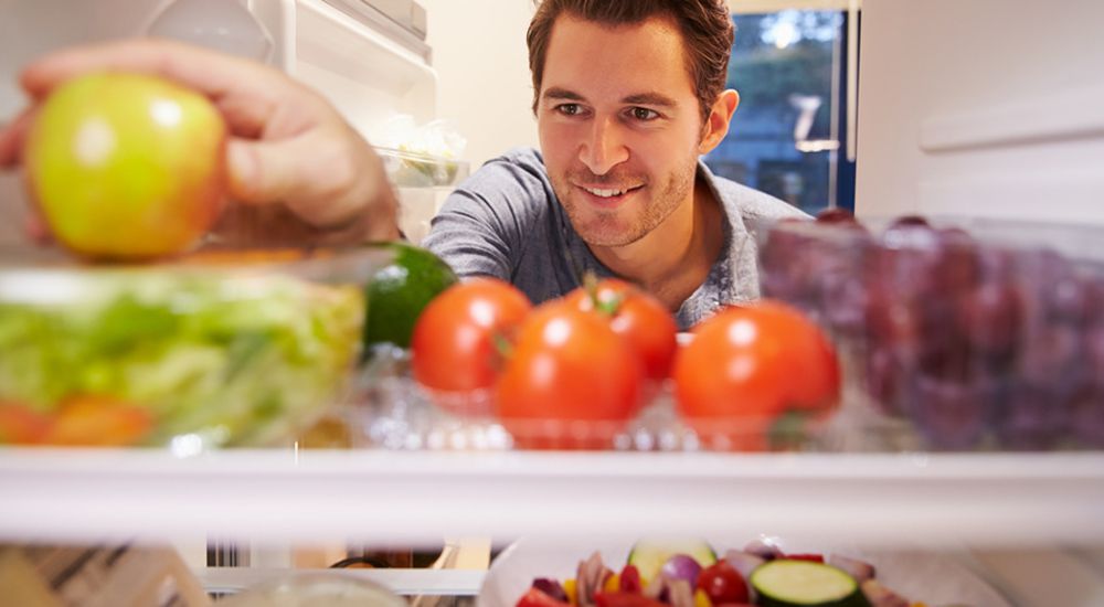 Homme prenant une pomme dans un frigo