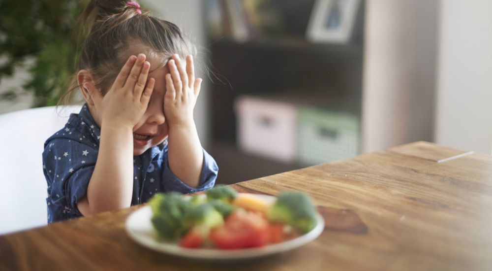 Petite fille qui refuse de manger des légumes