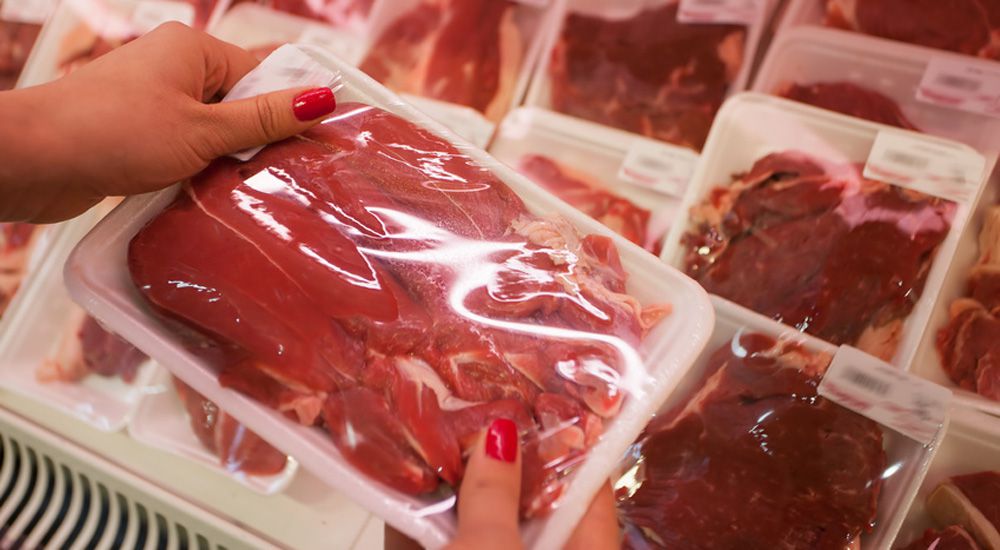 Packaged meat with woman hand in the supermarket