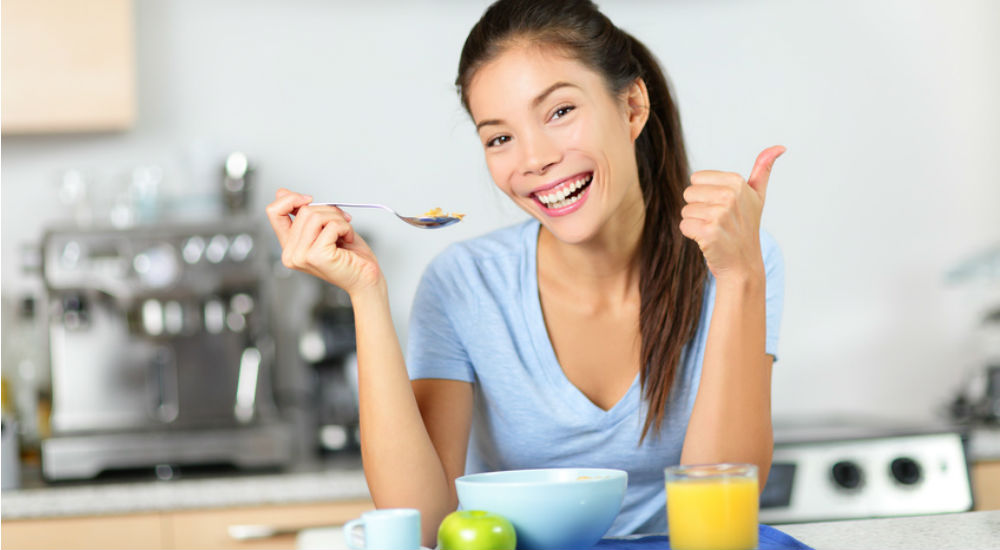 Femme souriante prenant son petit déjeuner