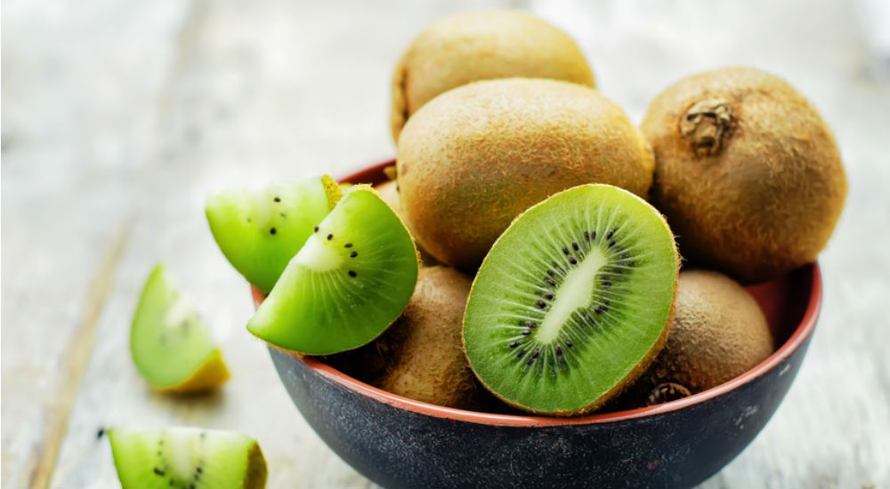 Des kiwis entier et coupées en morceaux dans une coupelle.