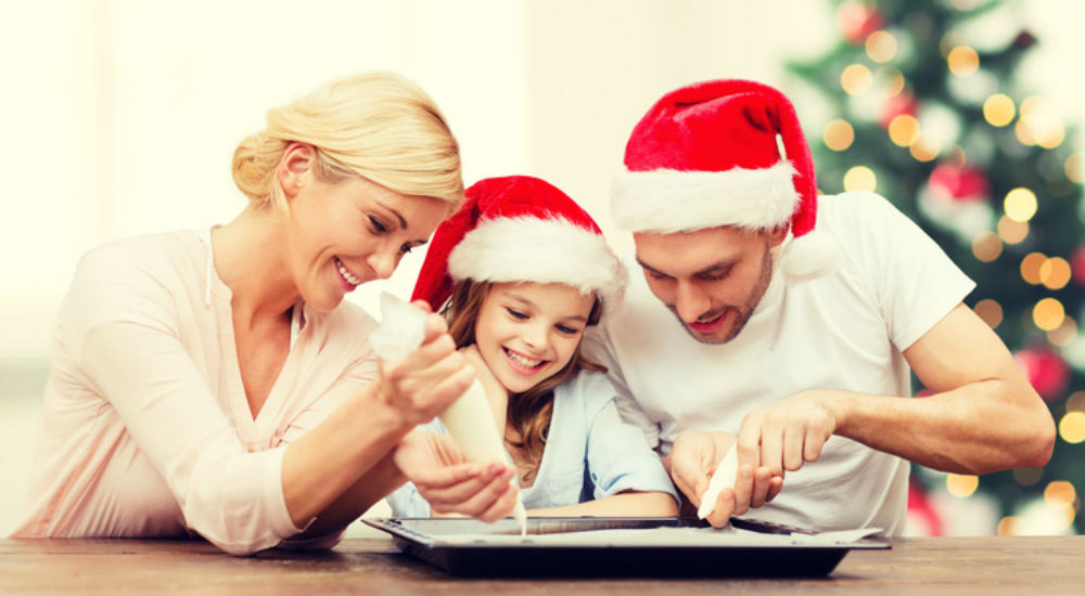 deux parents et leur fille qui cuisinent pour Noël