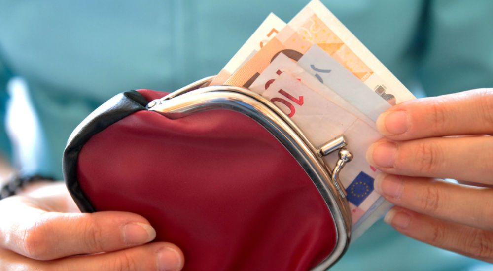 La main d'une femme sort un billet de banque du porte monnaie.