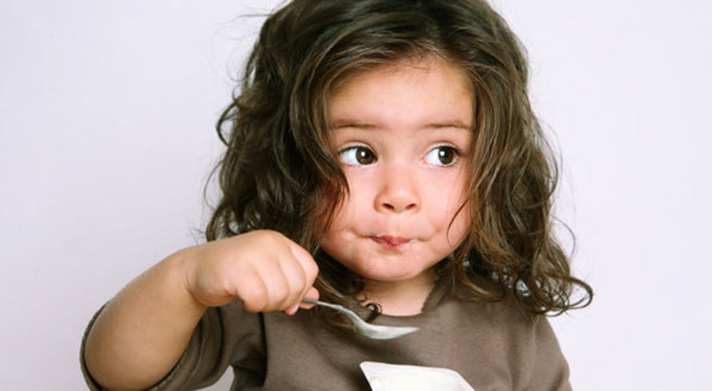 Une jeune fille mange de la soupe à la cuillière