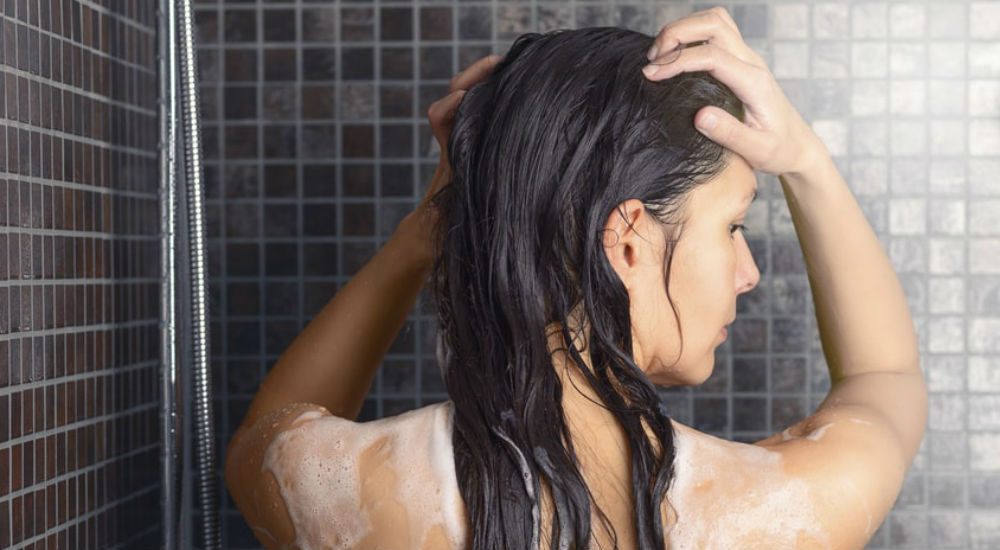 Une femme sous la douche se lave les cheveux