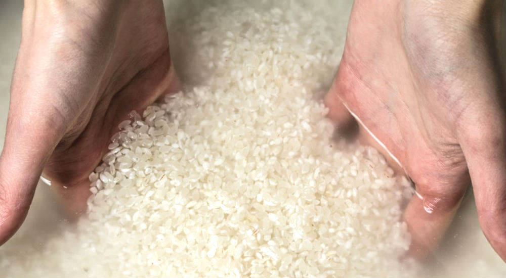 des mains de femme dans de l'eau de riz
