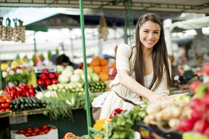 une femme choisit ses légumes au marché