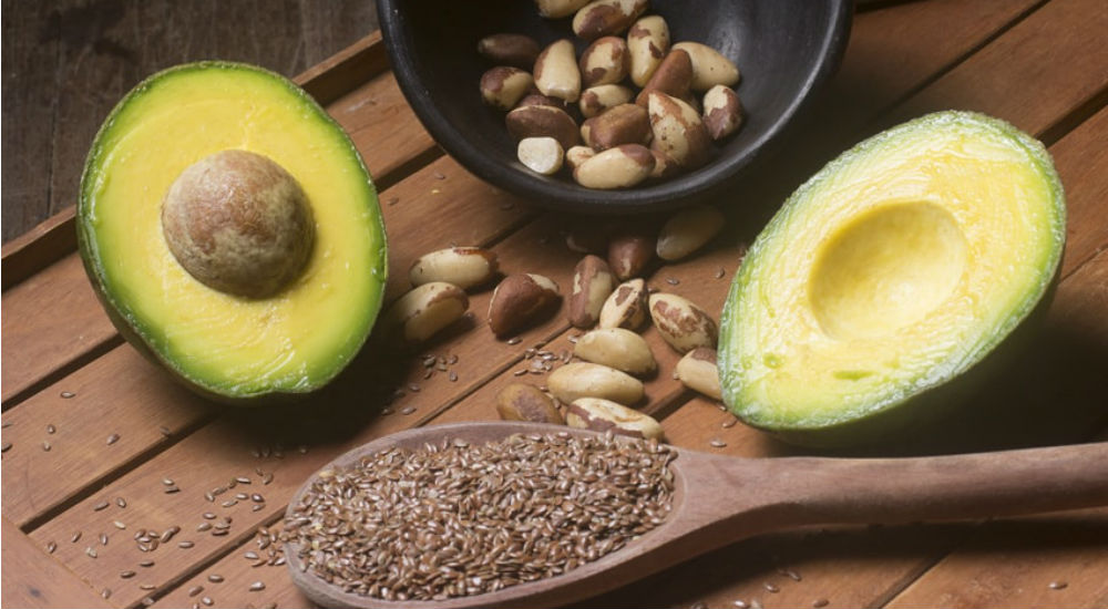 un avocat, des amandes et des graines de lin sur une table