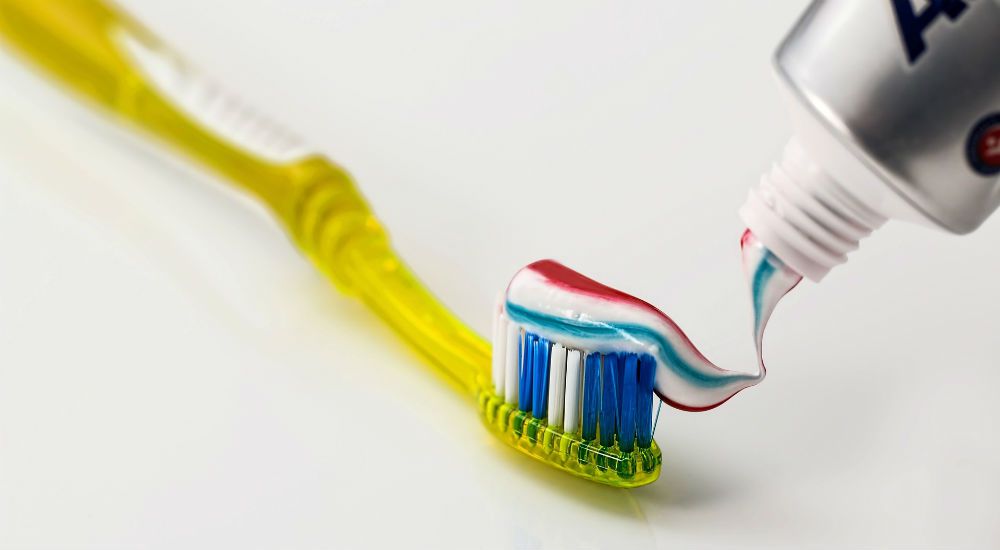 une brosse à dent jaune avec du dentifrice dessus