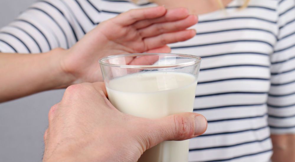 une femme repousse de la main un verre de lait