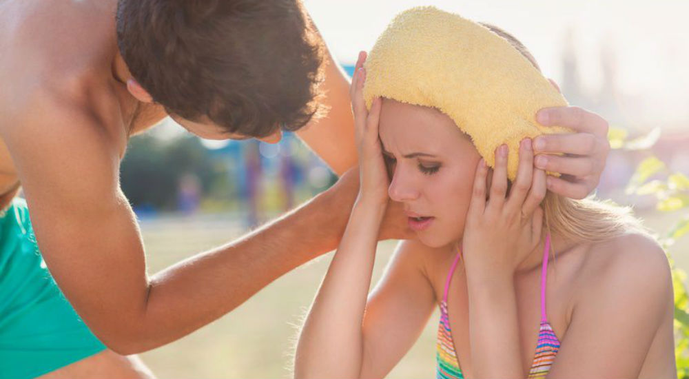 une femme ferme les yeux et a une serviette jaune sur la tête. Un homme se penche vers elle