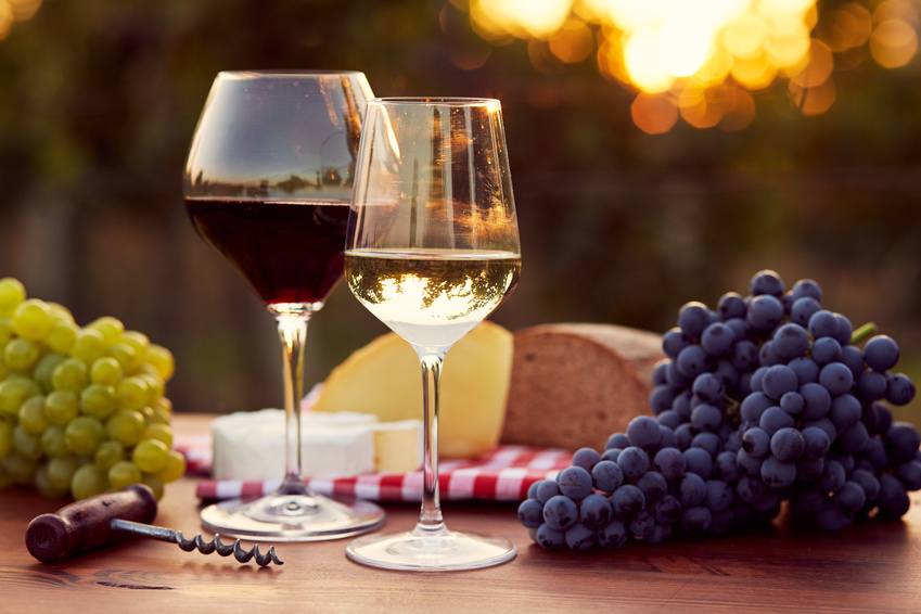 deux verres de vins posés sur une table avec des grappes de raisin