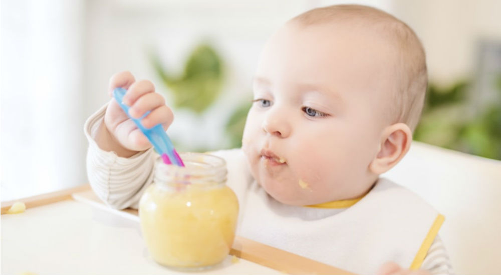 un bébé mange un petit pot