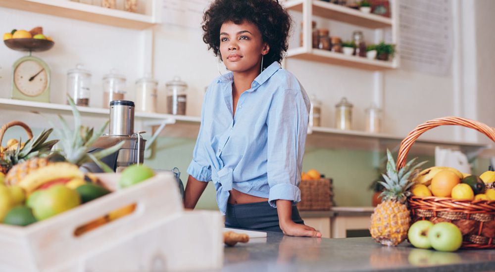 Femme souriant dans sa cuisine entourée de bocaux