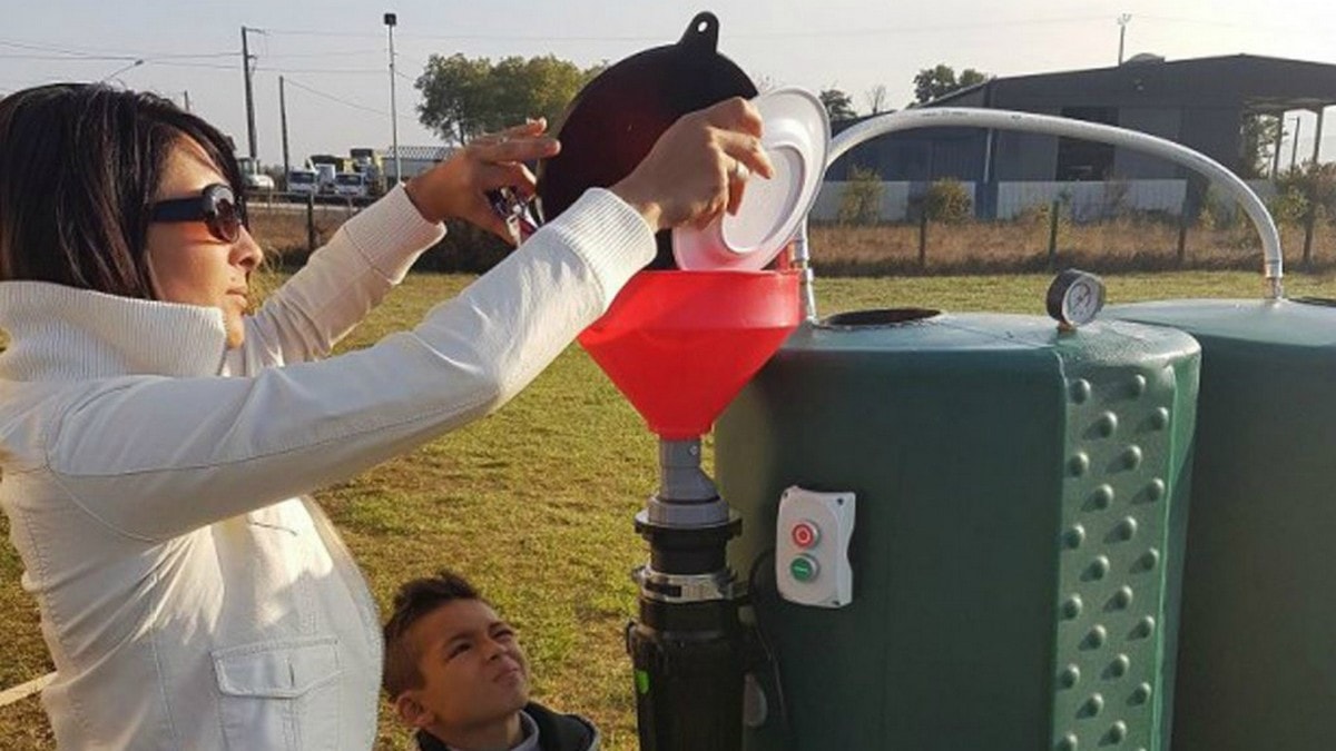 une femme en train de jeter des déchets organiques dans le méthaniseur domestique