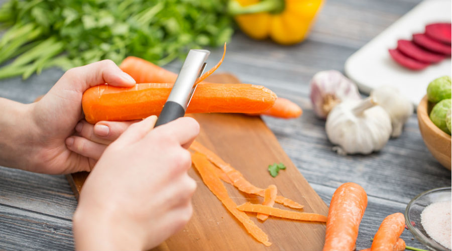 une personne épluche des carottes pour faire la cuisine