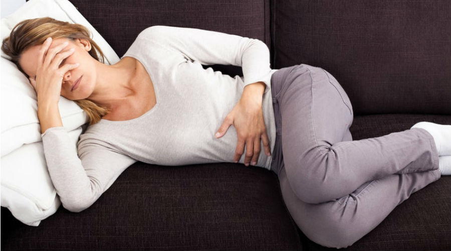 une femme allongée sur le canapé a des règles douloureuses